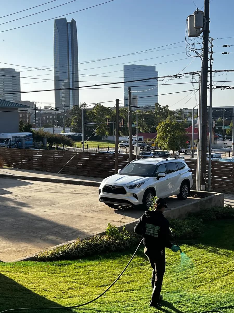 Greenline technician applying green-marked liquid treatment to commercial turf near downtown Oklahoma City
